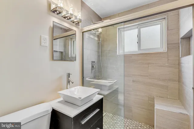 a bathroom with a granite countertop sink toilet and mirror