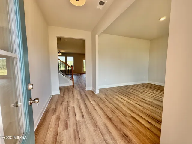 a view of a hallway with wooden floor and a bathroom