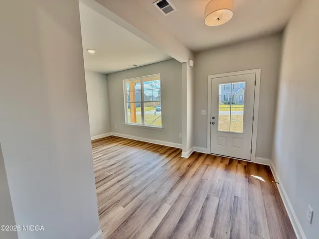 an empty room with wooden floor and windows