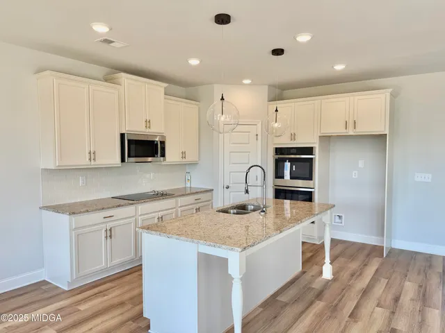 a kitchen with stainless steel appliances granite countertop a sink stove microwave and refrigerator