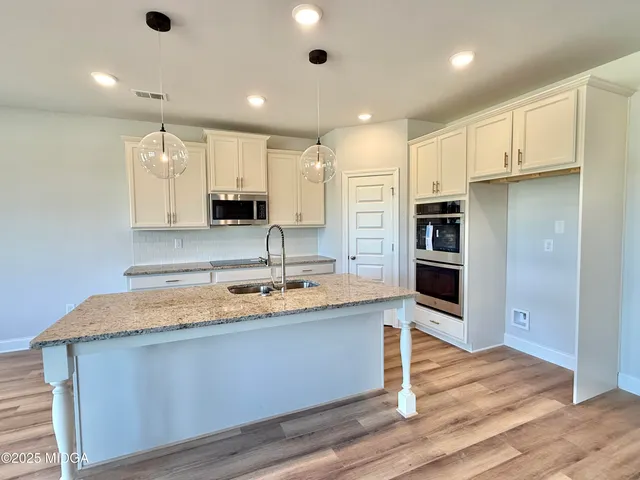 a large kitchen with stainless steel appliances granite countertop a sink a stove and a refrigerator