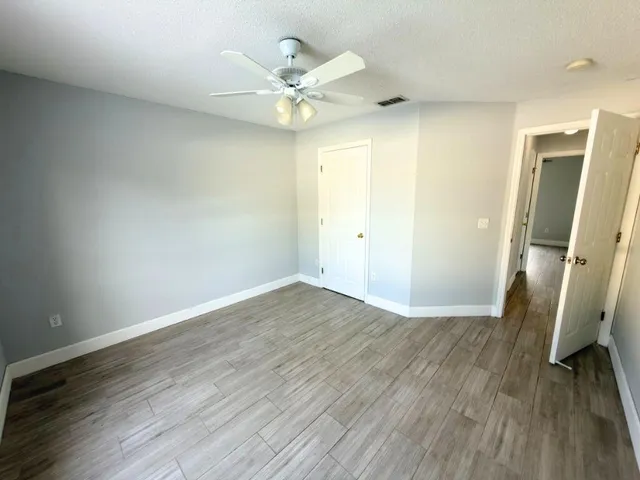 an empty room with wooden floor and a ceiling fan