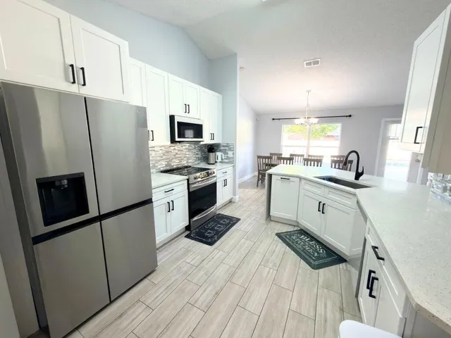 a kitchen with a sink a refrigerator a microwave and cabinets