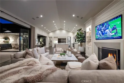 a living room with couches a fireplace and kitchen view