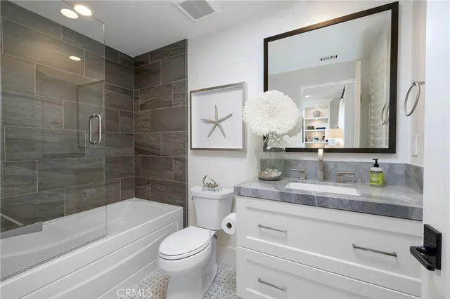 a bathroom with a granite countertop sink mirror toilet and bathtub