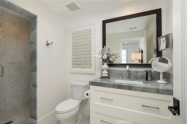a bathroom with a granite countertop toilet sink and mirror
