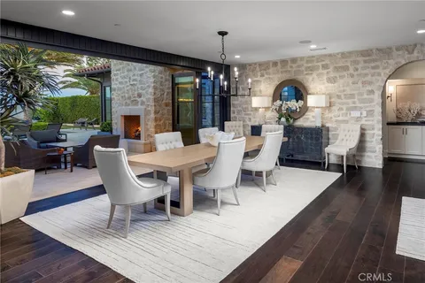 a dining room with furniture wooden floor a rug a potted plant and a chandelier