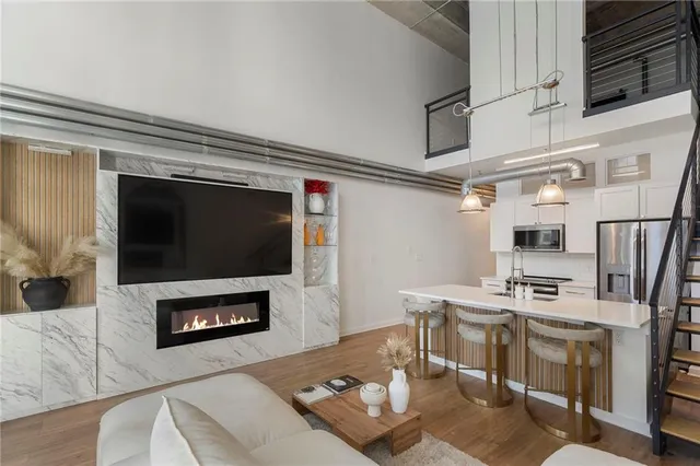 a living room with stainless steel appliances furniture a fireplace and a flat screen tv