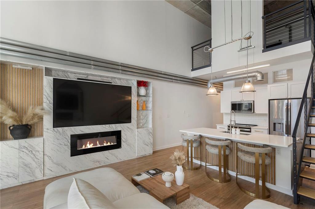 a living room with stainless steel appliances furniture a fireplace and a flat screen tv