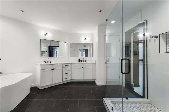a bathroom with a tub shower sink and mirror