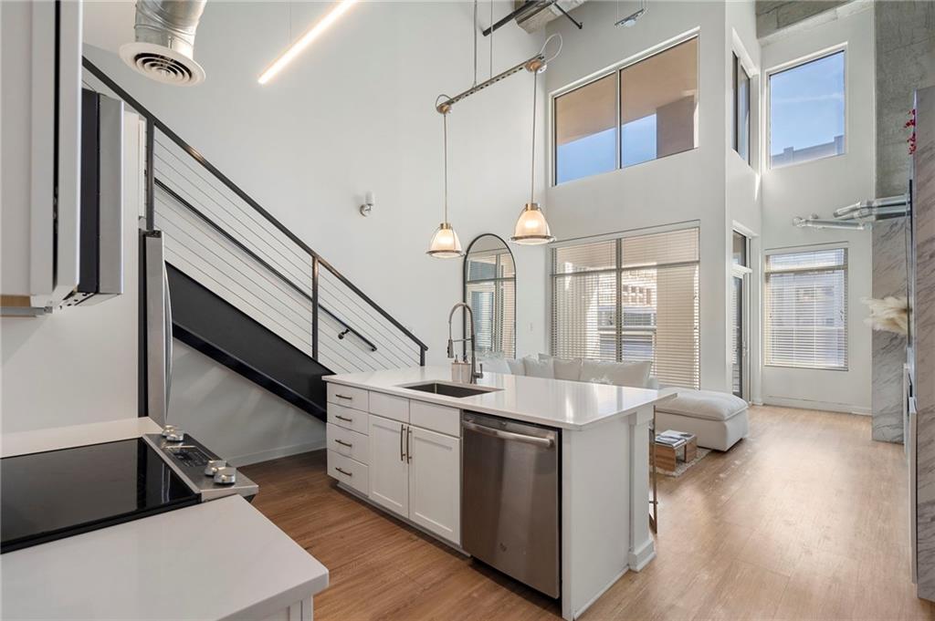 260 18th Street Northwest, Unit 10224 Atlanta, GA 30363 - Photo 10 of 47 a kitchen with stainless steel appliances a sink dishwasher a stove a dining table and chairs with wooden floor