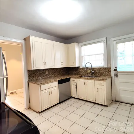 a kitchen with granite countertop white cabinets sink and stainless steel appliances