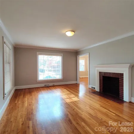 an empty room with wooden floor fireplace and windows