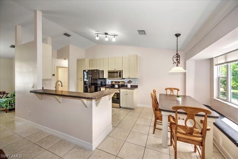 9058 Henry Road Fort Myers, FL 33967 - Photo 7 of 28 Kitchen featuring cream cabinets, kitchen peninsula, stainless steel appliances, track lighting, and light tile floors