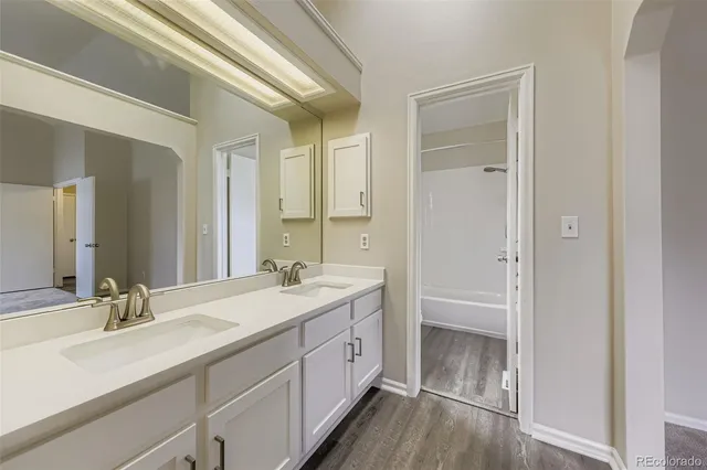 a spacious bathroom with a double vanity sink a mirror and a bathtub