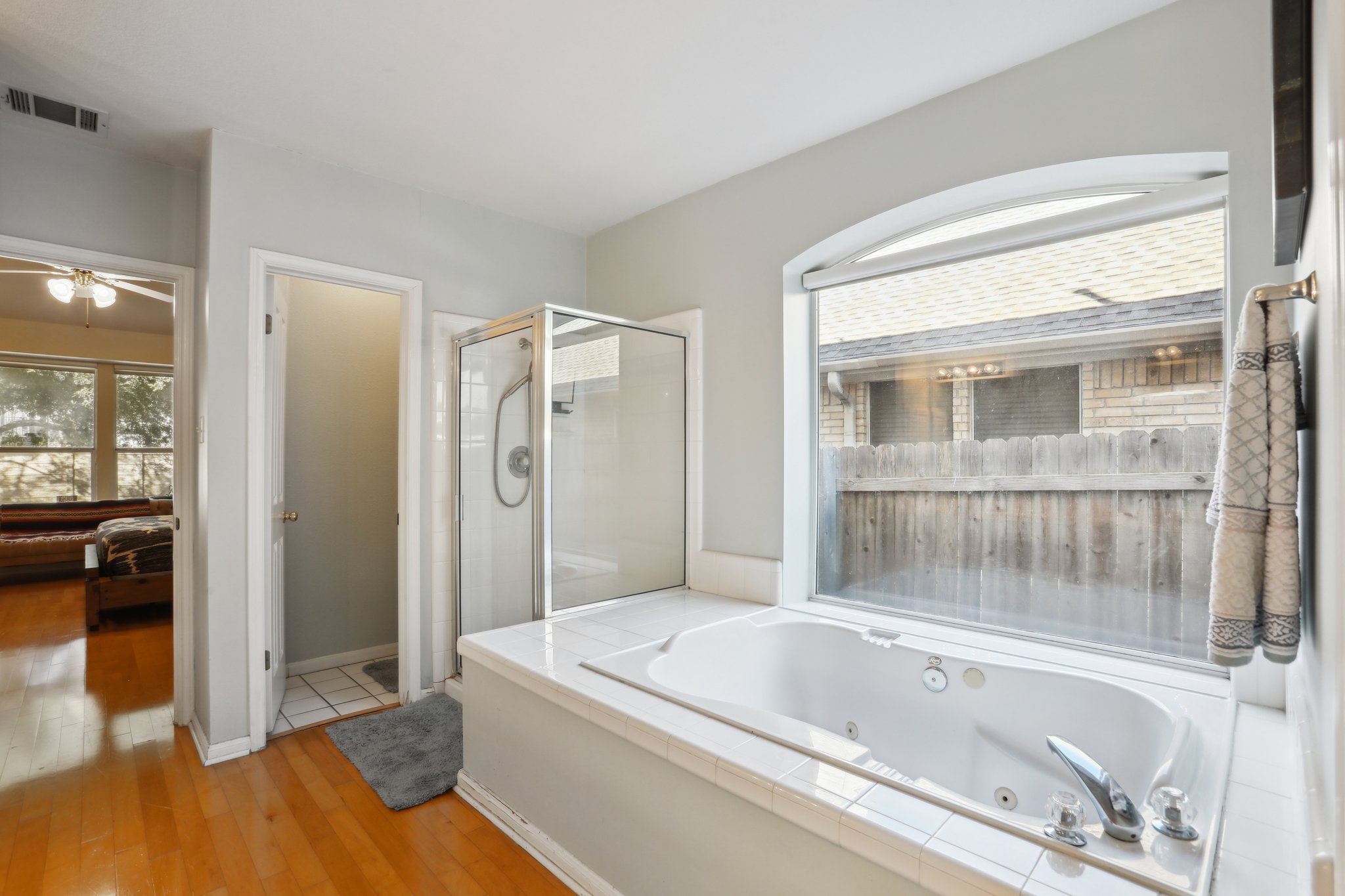 13541 Anarosa Loop Austin, TX 78727 - Photo 13 of 27 Soaking tub with a tiled surround, arched window, and glass-enclosed shower