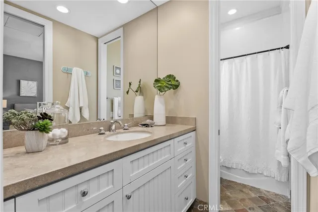 a bathroom with a granite countertop sink a mirror and a shower