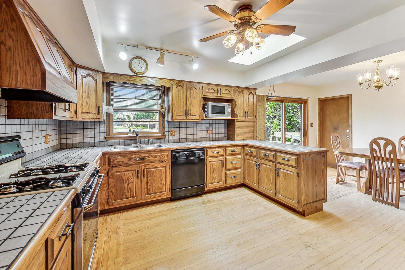 5701 Lenox Road Lisle, IL 60532 - Photo 8 of 24 a kitchen with stainless steel appliances granite countertop a stove top oven a sink a dining table and chairs with wooden floor