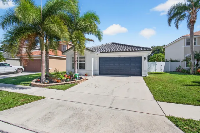 front view of a house with a yard and palm trees