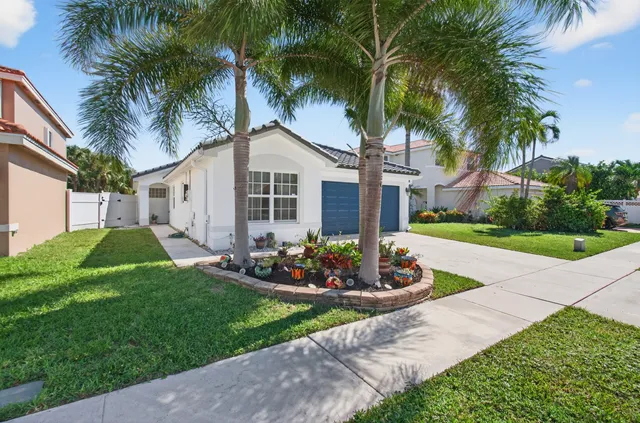 a view of a house with a yard and palm trees