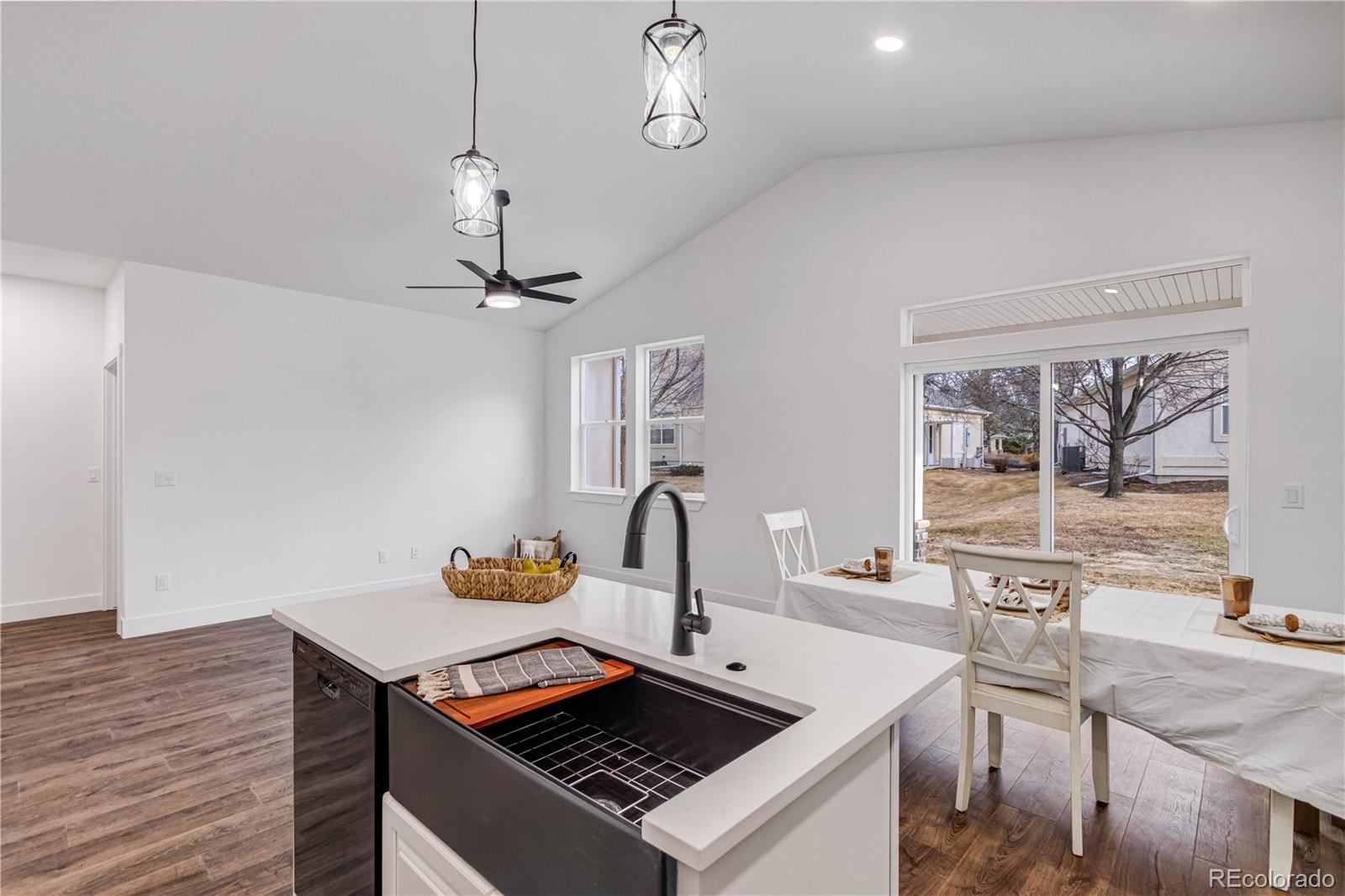 1230 Swainson Road Eaton, CO 80615 - Photo 8 of 35 a kitchen with a stove a sink and a dining table with wooden floor