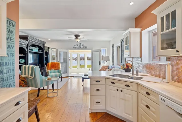 a kitchen with stainless steel appliances kitchen island granite countertop a stove a sink a dining table and chairs with wooden floor