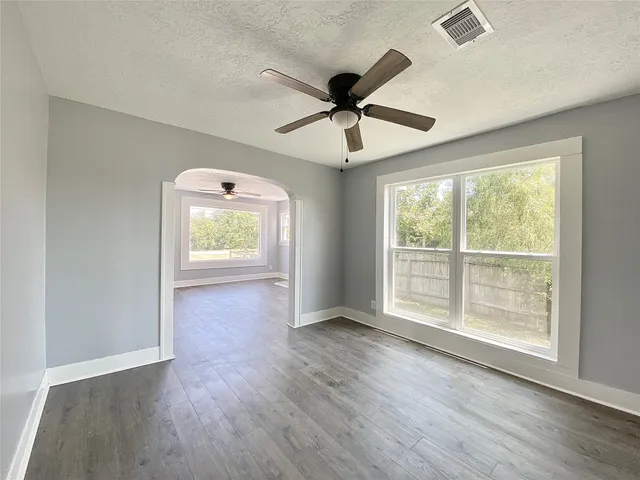 a view of an empty room with a window and wooden floor