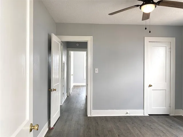 an empty room with wooden floor fan and windows