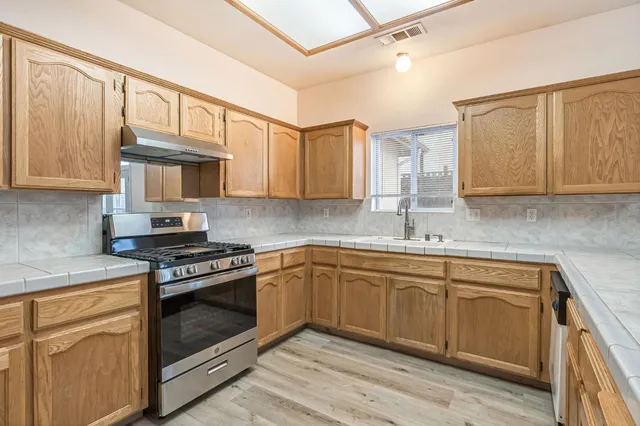 a kitchen with stainless steel appliances granite countertop a sink stove and cabinets