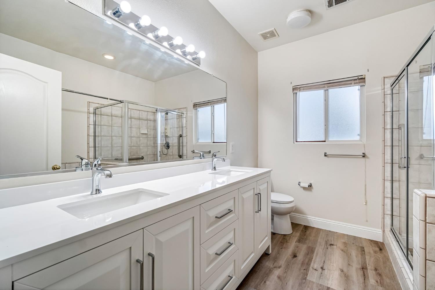 2095 Independence Place Hanford, CA 93230 - Photo 7 of 35 a bathroom with a double vanity sink a toilet and a mirror