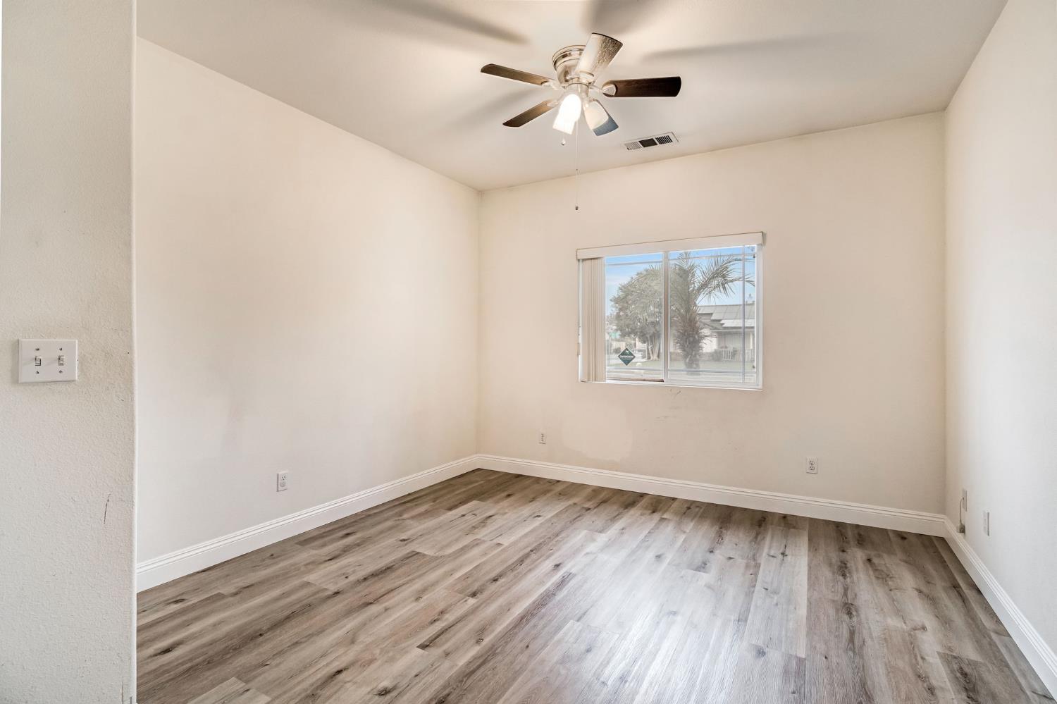 2095 Independence Place Hanford, CA 93230 - Photo 9 of 35 an empty room with wooden floor ceiling fan and window
