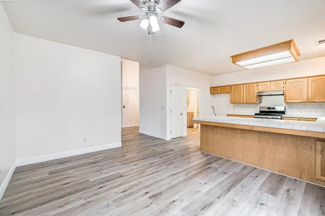 a view of a kitchen with wooden floor and a ceiling fan