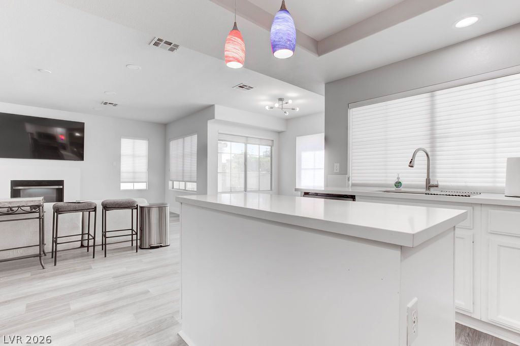 1 Rising Sun Court Henderson, NV 89074 - Photo 9 of 47 An open-concept living space integrates a functional kitchen with a cozy entertainment area, featuring light-toned flooring.