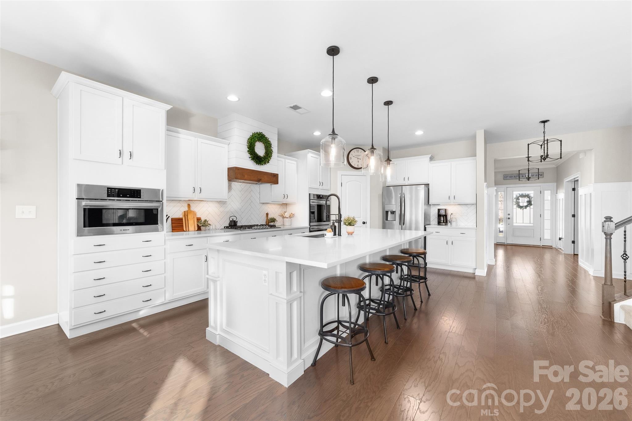 17549 Julees Walk Lane Davidson, NC 28036 - Photo 11 of 48 a kitchen with stainless steel appliances kitchen island granite countertop a stove a sink a refrigerator and white cabinets with wooden floor