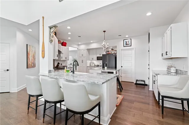 a kitchen with stainless steel appliances kitchen island granite countertop a table chairs and a refrigerator