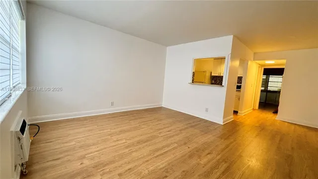 a view of an empty room with wooden floor and a window