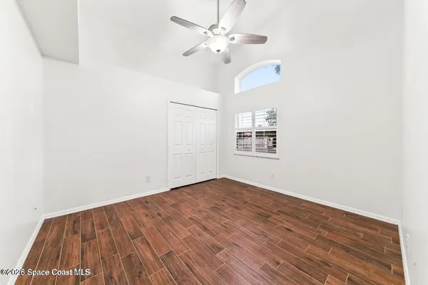 an empty room with wooden floor ceiling fan and windows