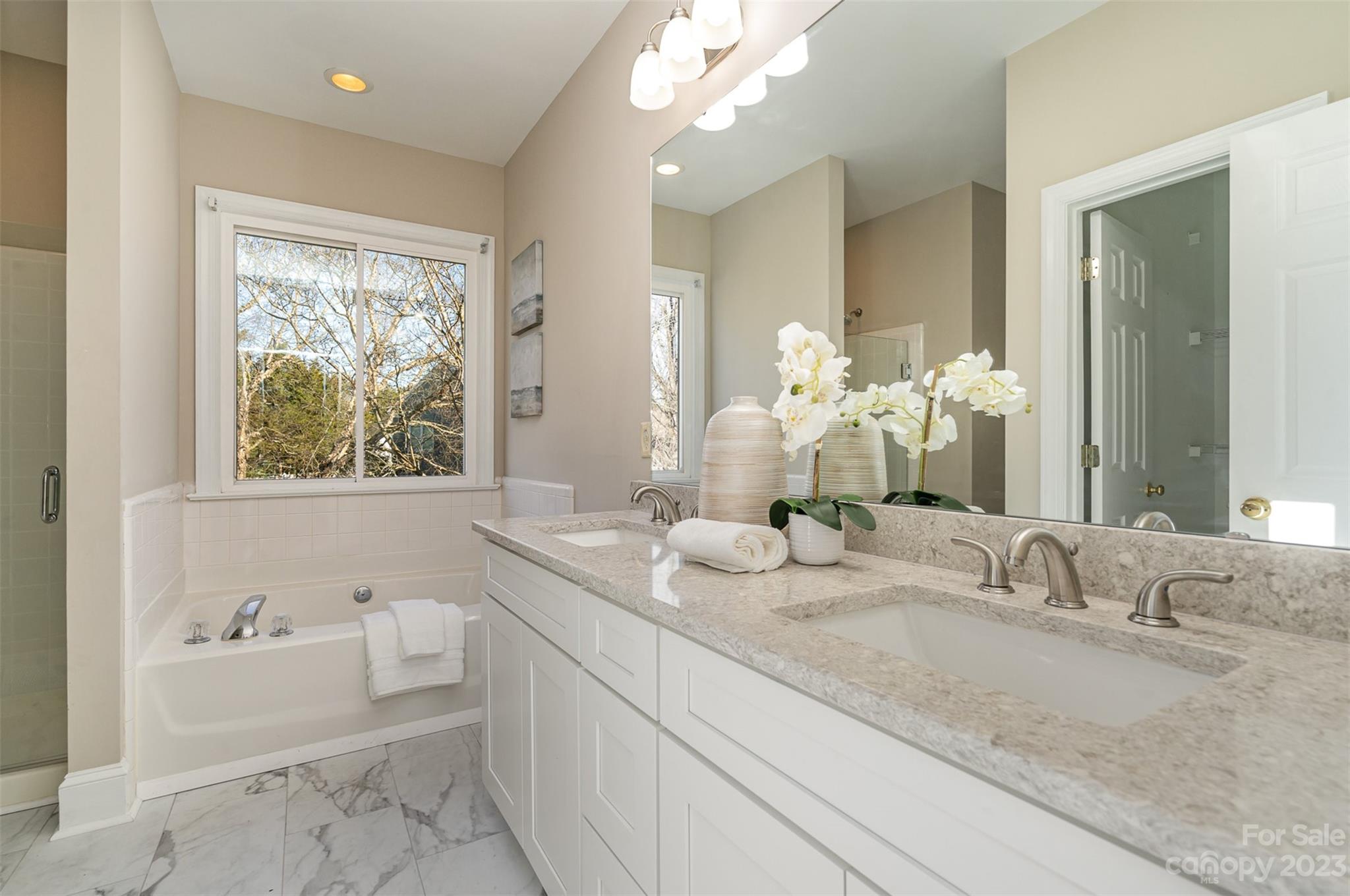 2906 Saintfield Place Charlotte, NC 28270 - Photo 21 of 37 a bathroom with a granite countertop sink a large mirror a bathtub and next to a window