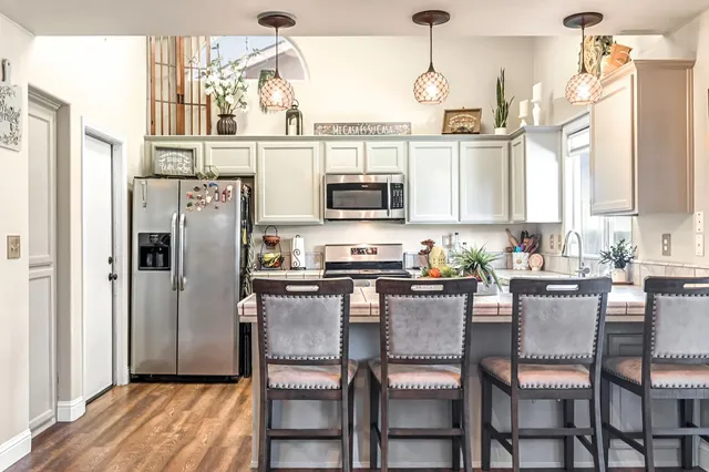 a kitchen with stainless steel appliances granite countertop a dining table chairs refrigerator and microwave