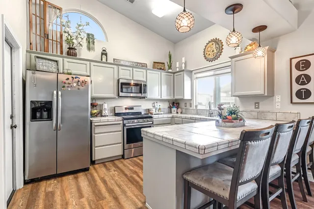 a kitchen with stainless steel appliances granite countertop a refrigerator a stove a sink dishwasher and a refrigerator with wooden floor