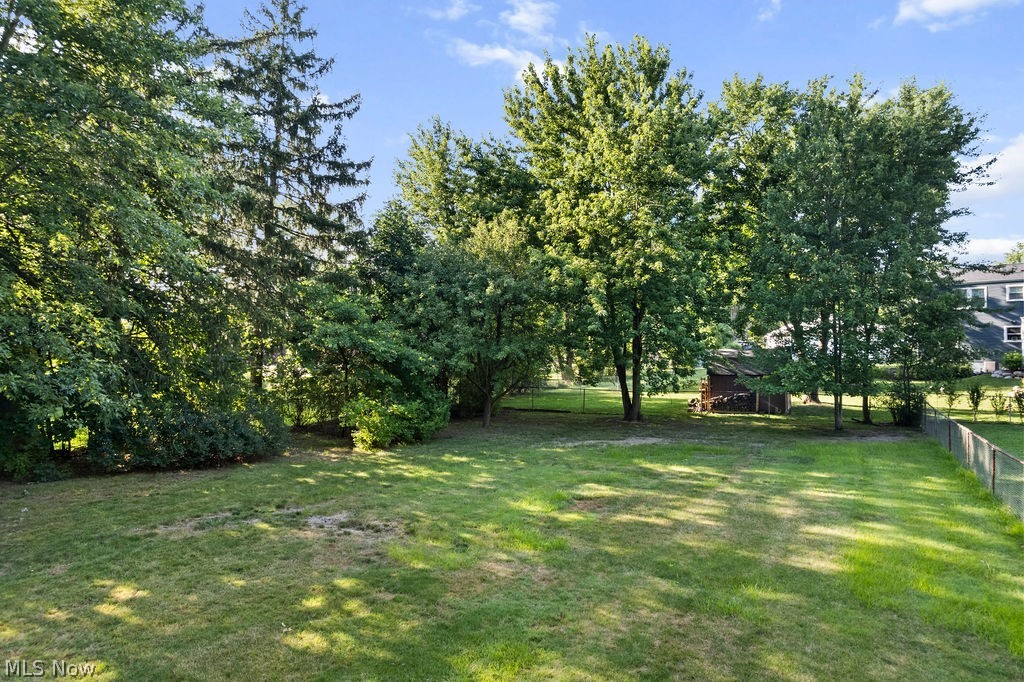 1903 Graham Road Stow, OH 44224 - Photo 29 of 29 Spacious green lawn featuring mature trees, partial fencing, and a storage shed