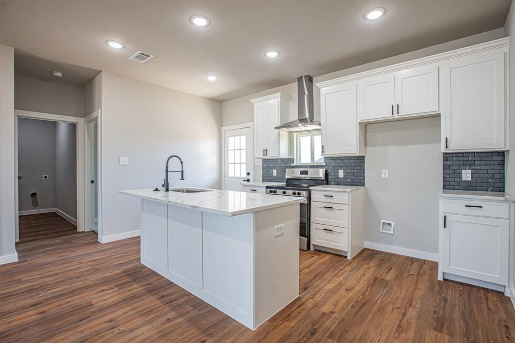 124 Brookview Drive Jacksboro, TX 76458 - Photo 4 of 34 a kitchen with white cabinets stainless steel appliances and wooden floor