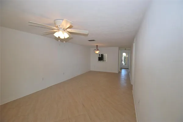 a view of an empty room with a chandelier fan
