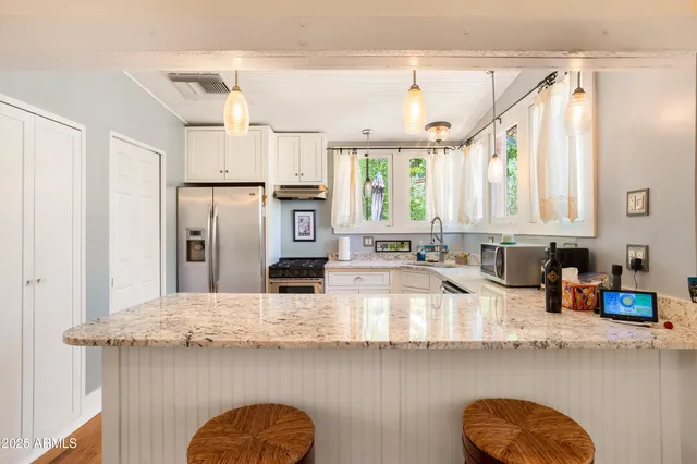 a kitchen with stainless steel appliances granite countertop a sink window and cabinets
