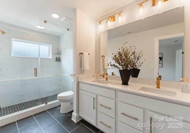 a bathroom with a double vanity sink toilet and shower