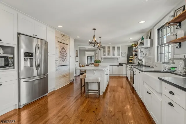 a kitchen with stainless steel appliances granite countertop a refrigerator a stove oven a sink dishwasher and white cabinets with wooden floor