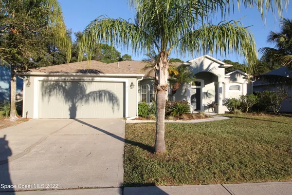 a view of a house with a yard and palm trees