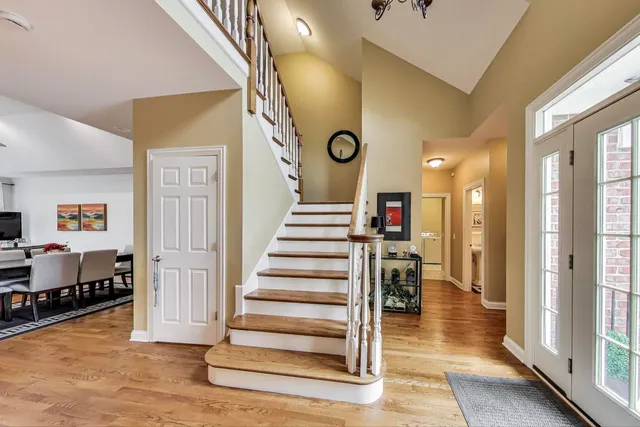 a view of a hallway to a livingroom with wooden floor and stairs