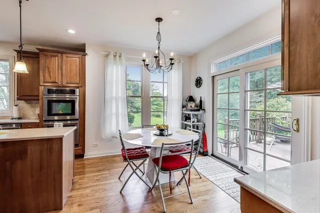 a kitchen with stainless steel appliances kitchen island granite countertop a refrigerator a stove top oven and a dining table with wooden floor