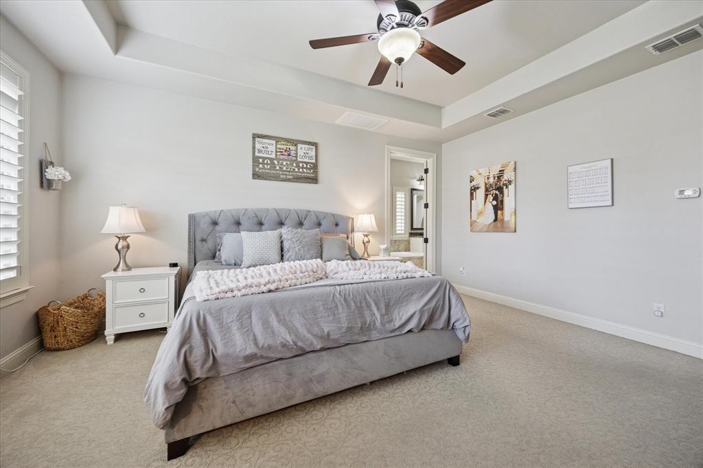 580 Butchart Drive Prosper, TX 75078 - Photo 17 of 40 Bedroom with carpet floors, a raised ceiling, baseboards, ensuite bathroom, and a ceiling fan
